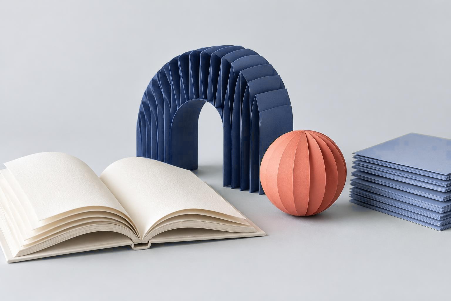 An open book and sculptural paper forms in blue and coral